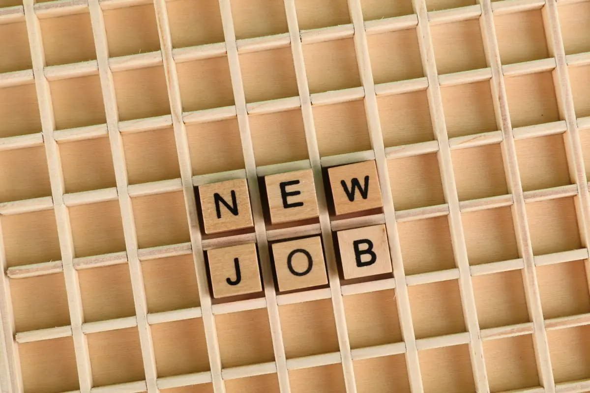 Discover the excitement of a new job with wooden letter tiles spelling 'NEW JOB' on a grid.