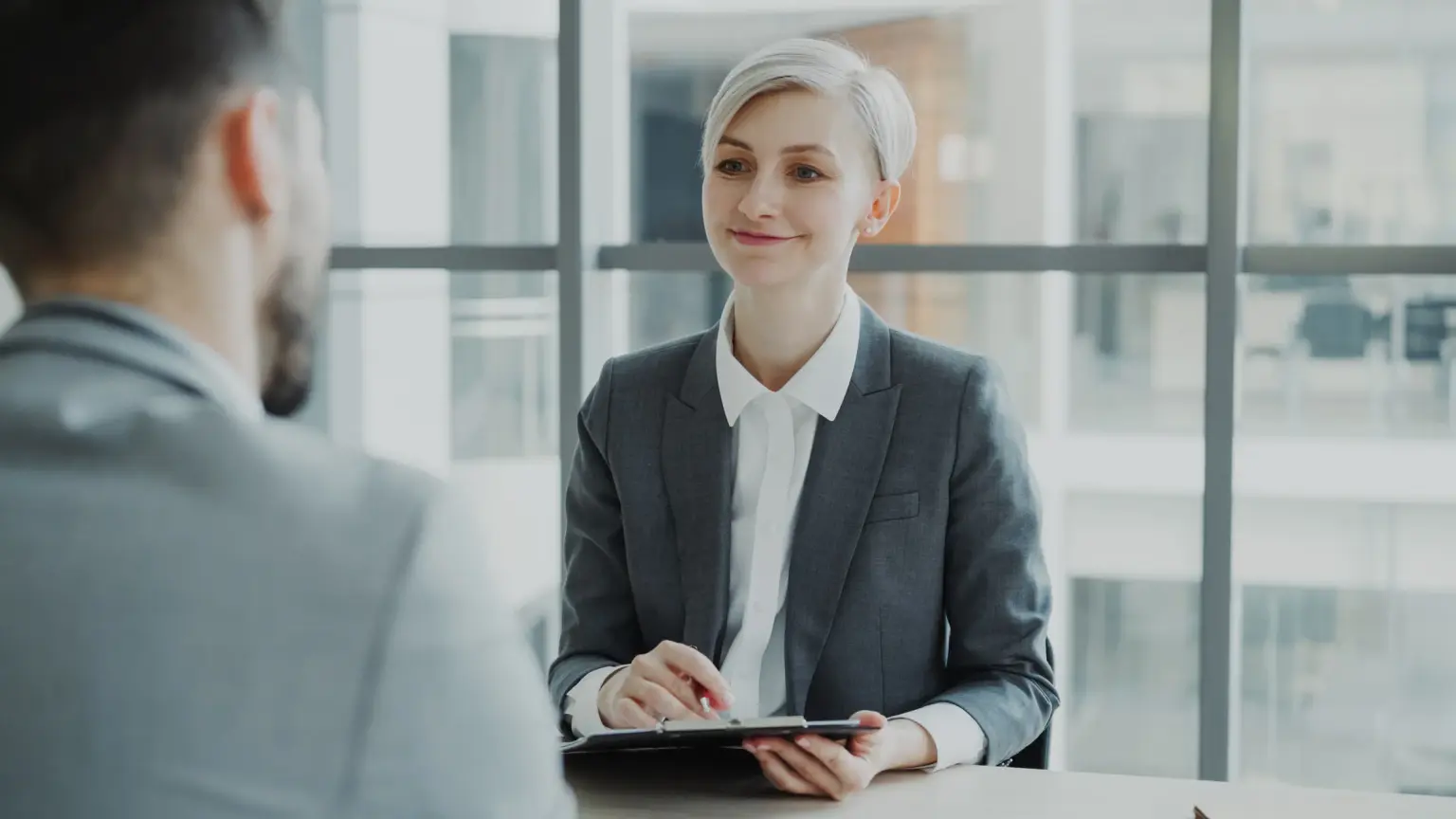 modern bir ofis binasında mülakat görüşmesi yapan profesyoneller, bir tesis yöneticisinin teknik planları incelediği an