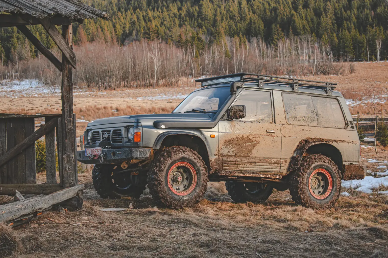 4x4 SUV parked on a muddy trail in Covasna, Romania, amidst a scenic wooded landscape.