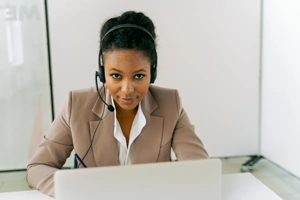 Confident woman in a call center setting, wearing a headset and suit, ready to assist.