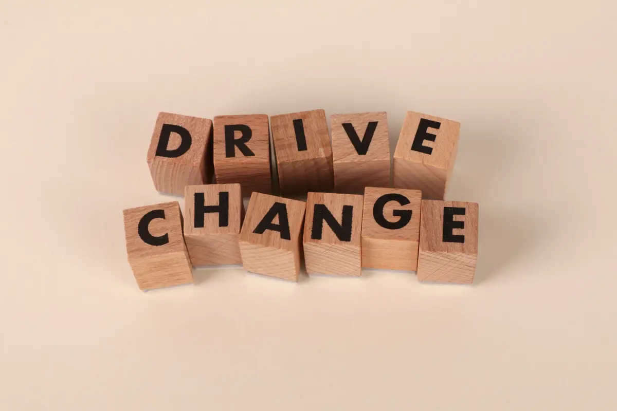 Wooden blocks spelling 'Drive Change' on a neutral background, symbolizing motivation and growth.