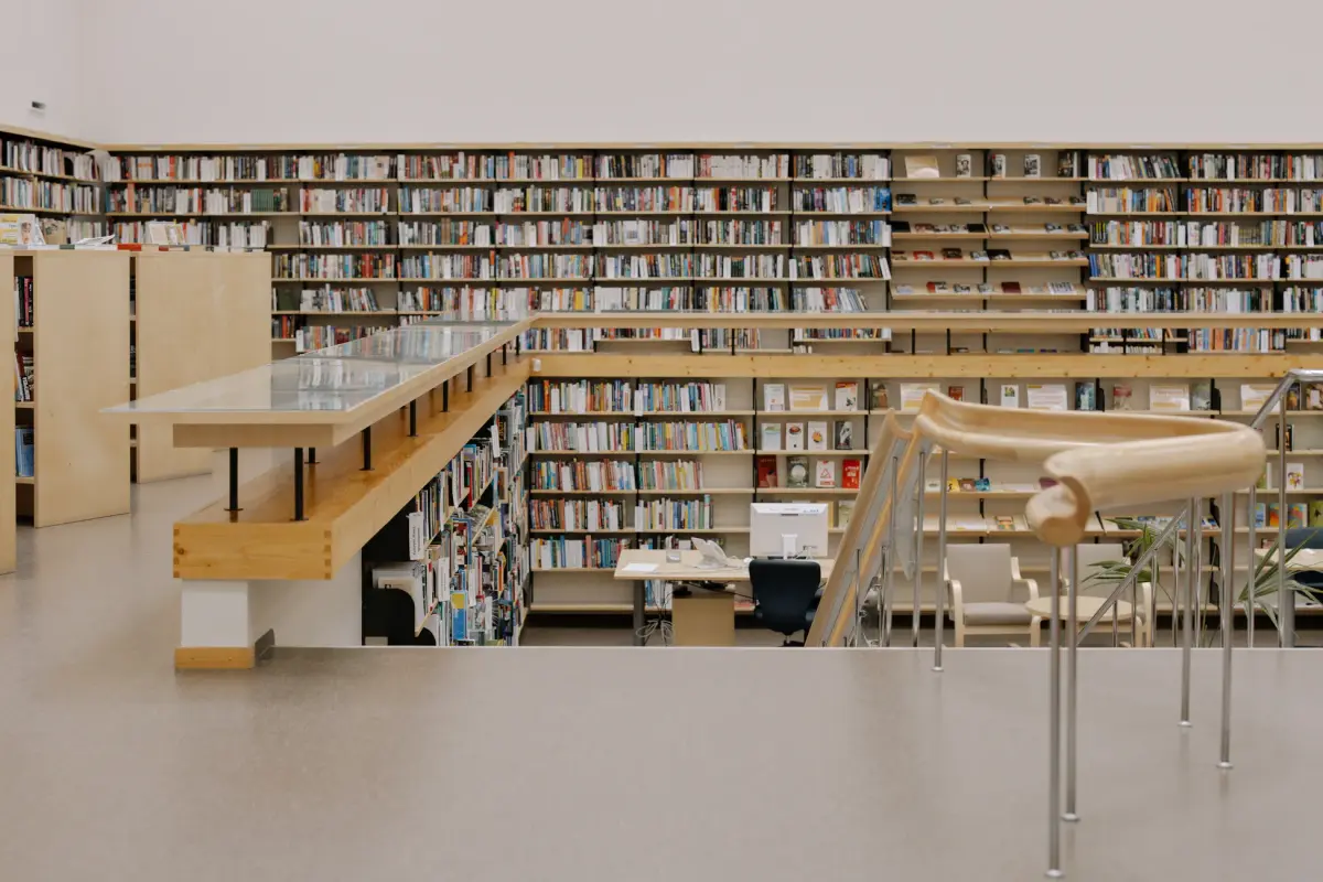Spacious modern public library interior with tall bookshelves and study areas.