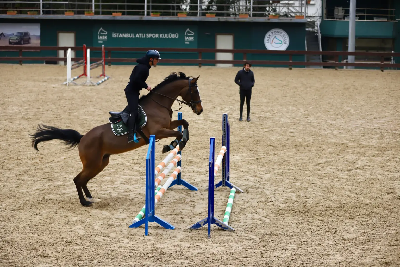 A horse and rider perform a jump at the Istanbul Horse Sports Club arena.