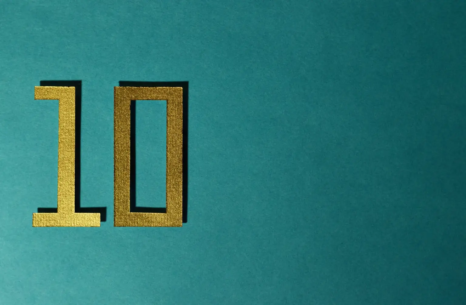 Stylish gold number ten on a textured teal background for design concepts.