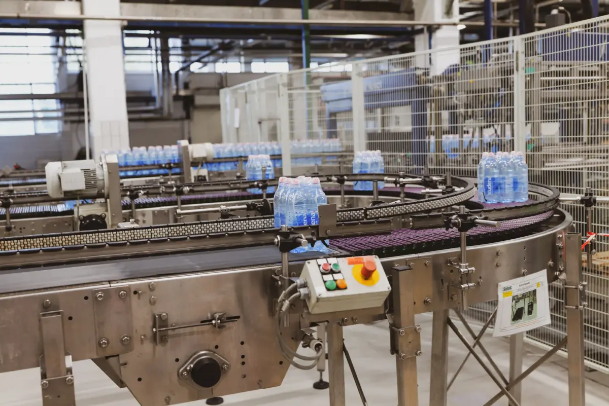 Water bottles being processed on an automated conveyor in a modern factory setting.