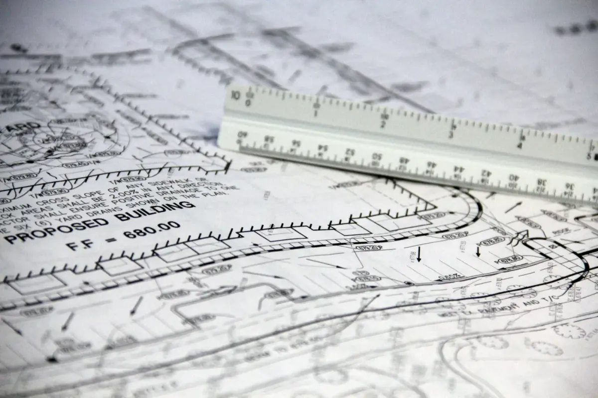 Detailed close-up of architectural blueprints with scale ruler, showing building plans and measurements.