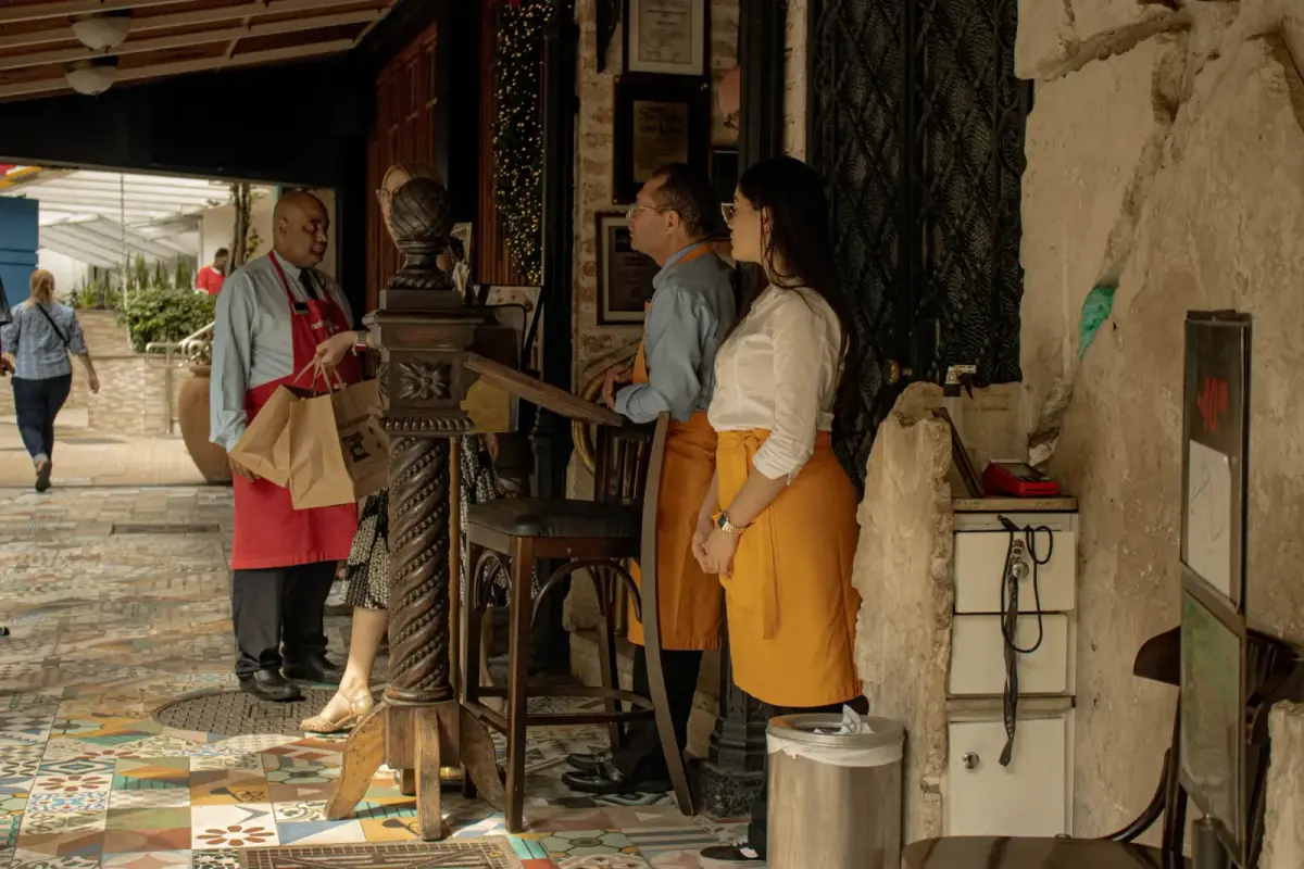 Restaurant staff interacting with customers at entrance, providing a welcoming atmosphere.