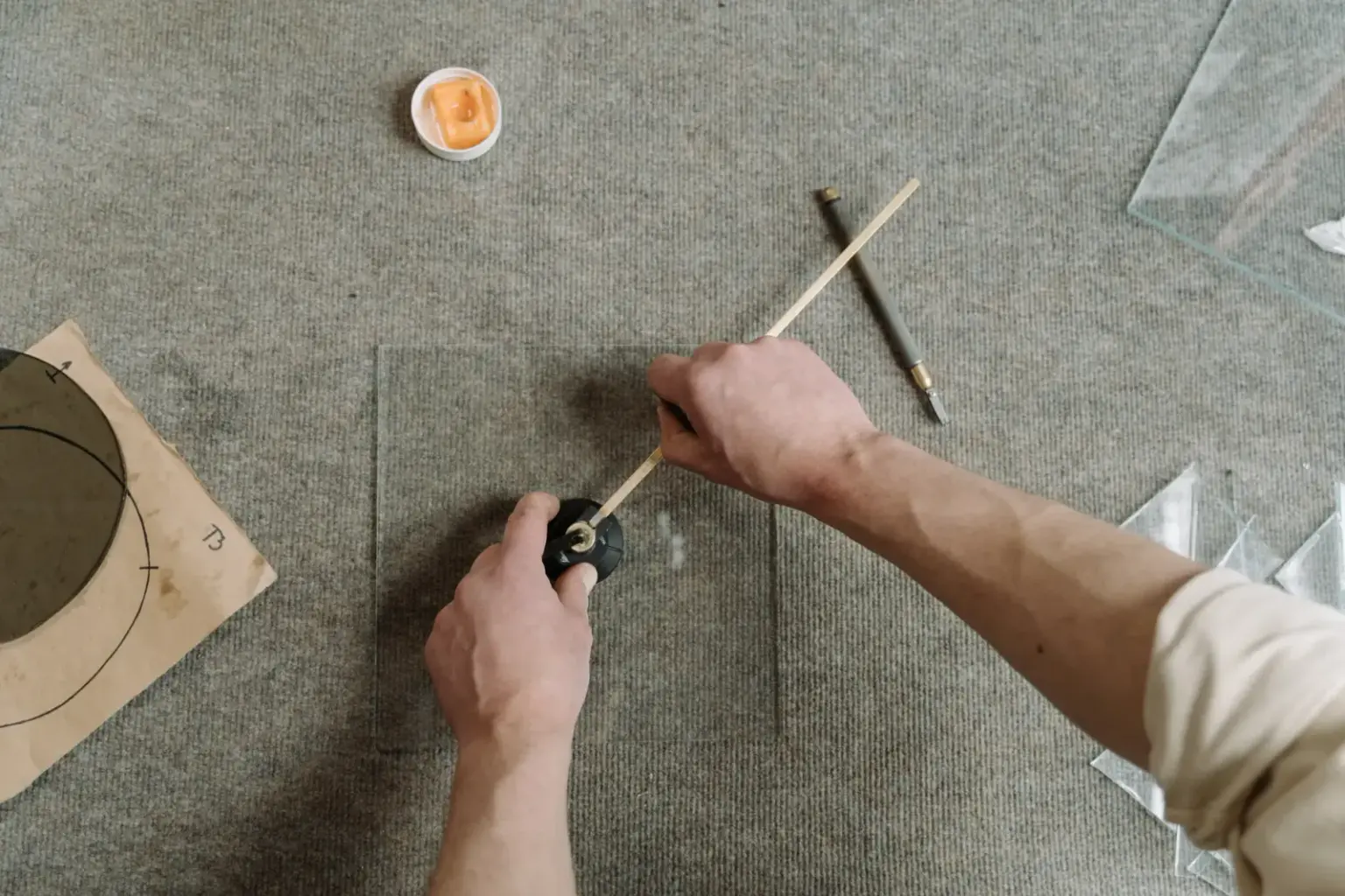 Close-up of artisan hands carefully cutting glass on a workshop table.